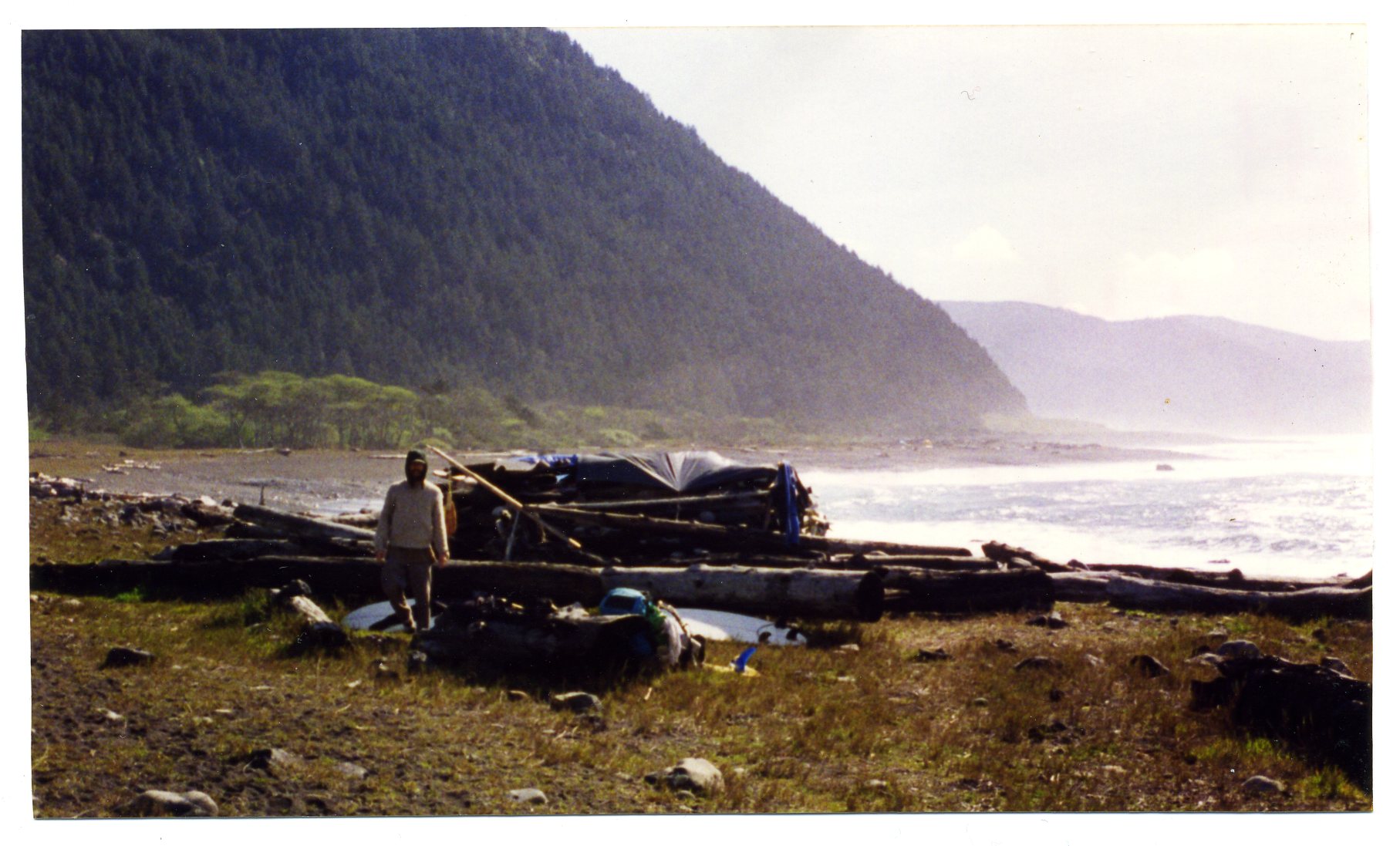 Artist Matt Beard emerging from a makeshift log shelter on the Lost Coast of Northern California circa 1996